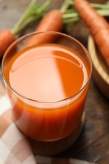 Healthy carrot juice in glass and fresh vegetables on table, closeup