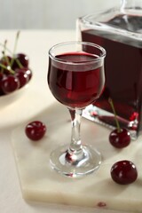 Delicious cherry liqueur and berries on white table, closeup