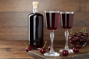 Delicious cherry liqueur and berries on wooden table
