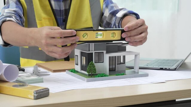 Professional architect team and engineer discuss about architectural project on meeting table with safety helmet, wooden block and architectural document scatter around. Closeup. Delineation.