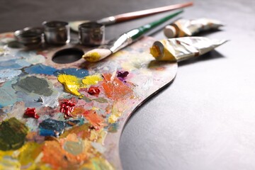 Obraz premium Artist's palette, brushes and paints on grey table, closeup. Space for text