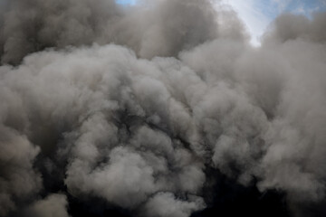 Toxic black smoke from fire against sky, burning plastic.