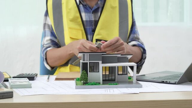 Professional architect team and engineer discuss about architectural project on meeting table with safety helmet, wooden block and architectural document scatter around. Closeup. Delineation.