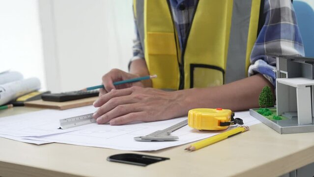 Professional architect team and engineer discuss about architectural project on meeting table with safety helmet, wooden block and architectural document scatter around. Closeup. Delineation.