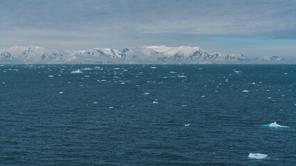 Beautiful Wide View of Antarctica Floating Icebergs Snow Covered Mountains Serene Nature Landscape...