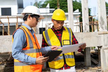 A team of construction engineers talks with managers and construction workers at the construction site. Quality inspection, plans, home and industrial building design projects