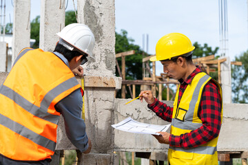 A team of construction engineers talks with managers and construction workers at the construction site. Quality inspection, plans, home and industrial building design projects