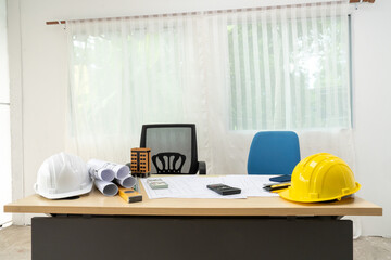 Professional team of architects and engineers discuss architectural project on conference table with hard hats, wooden blocks and architectural documents scattered around. Close-up. Drawing.