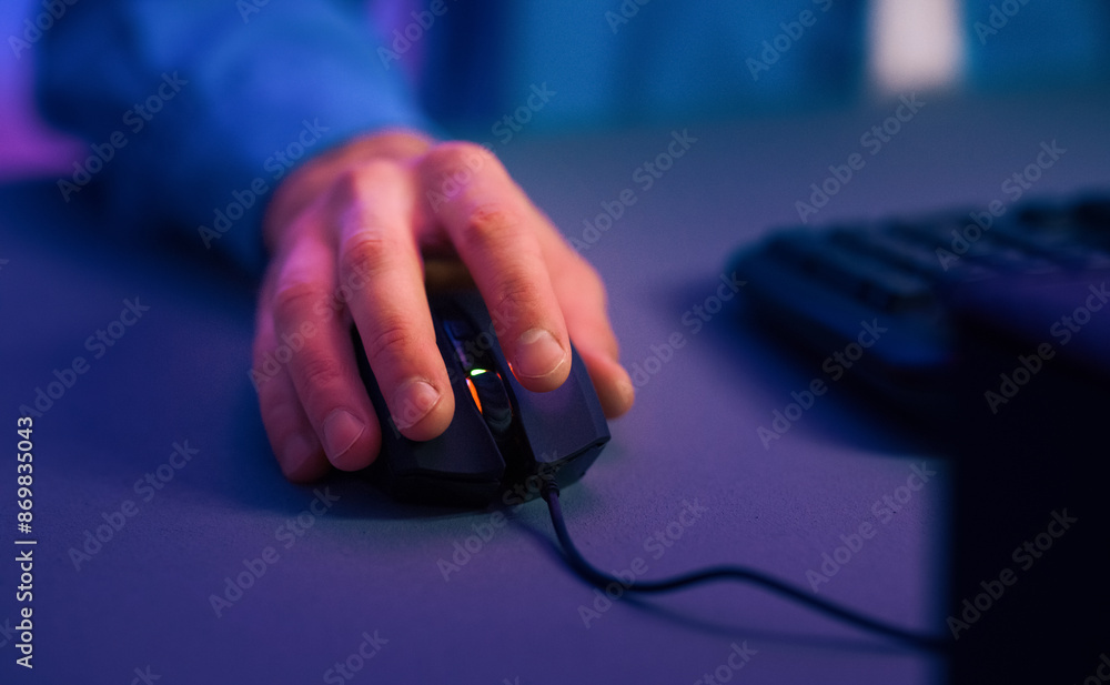 Poster This image shows a closeup of a hand using a computer mouse on a desk. The hand is positioned on the mouse and the fingers are gripping it. The mouse is black and has a red light on it.