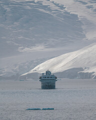 Antarctica Expedition Cruise Ship Sailing Towards Us with Huge Glacier Ice Wall Behind it. Iceberg...