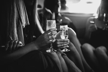 Girls holding glasses of champagne in a limousine, close-up