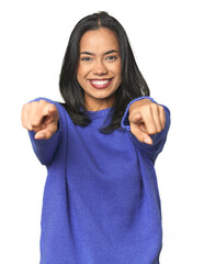 Simple portrait of a young Latina cheerful smiles pointing to front.