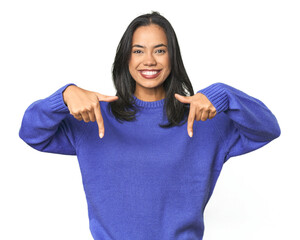 Simple portrait of a young Latina points down with fingers, positive feeling.