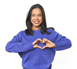 Simple portrait of a young Latina smiling and showing a heart shape with hands.