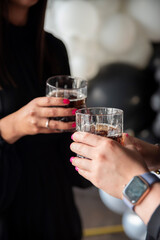 Women's hands hold glasses with whiskey and cola, close-up
