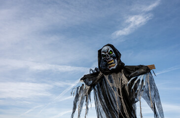 Human skeleton against blue sky. Grim Reaper Halloween Decoration.