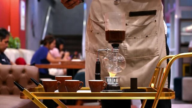 Close-up of a barista brewing syphon coffee with customers in the background