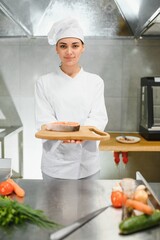 Portrait of young beautiful female chef in restaurant kitchen