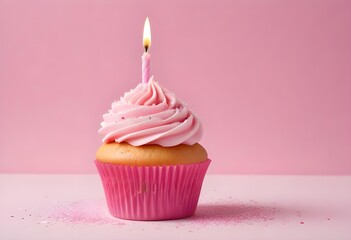 A pink birthday cupcake with a lit candle on a pink and white background with sparkles