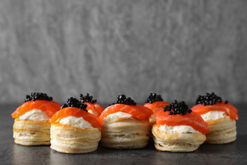 Delicious puff pastry with cream cheese, salmon and black caviar on grey table