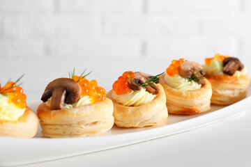 Delicious puff pastry with cream cheese, red caviar, mushrooms and dill on white table