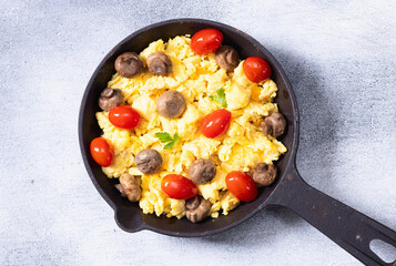 Homemade scrambled eggs with mushrooms and cherry tomatoes