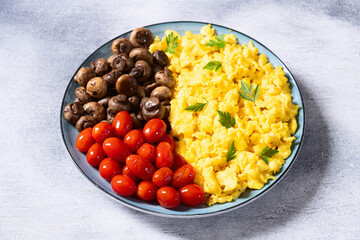 Homemade scrambled eggs with mushrooms and cherry tomatoes