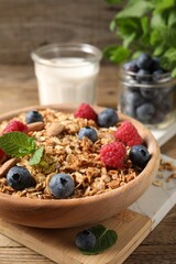 Tasty granola with berries, nuts and mint on wooden table