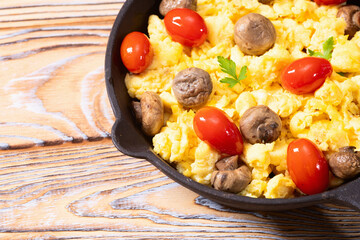 Homemade scrambled eggs with mushrooms and cherry tomatoes