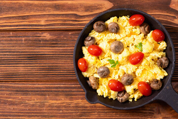 Homemade scrambled eggs with mushrooms and cherry tomatoes