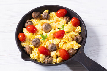 Homemade scrambled eggs with mushrooms and cherry tomatoes
