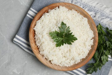 Tasty cooked rice in bowl with parsley on grey marble table, flat lay