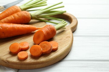 Whole and cut fresh carrots on white wooden table, closeup
