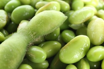 Raw green edamame pod and soybeans as background, closeup