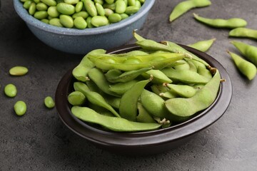 Raw green edamame soybeans and pods on grey table, closeup