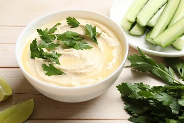 Tasty hummus with chickpeas in bowl and fresh products on wooden table, closeup