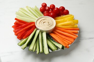 Tasty homemade hummus and different vegetables on white marble table