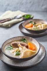 Traditional Jewish Kreplach soup with meat and carrot, gray background