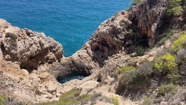 Overview on the Cala Moraig  in the Calpe area,  a stunning beach known for its crystal-clear turquoise waters, dramatic cliffs, and natural caves