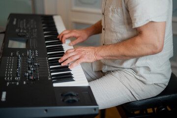 Older man playing classic piano synthesizer for a parti close up while wearing short sleeves