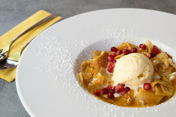 A plate of crepe suzette French pancakes with vanilla ice cream and pomegranates. 