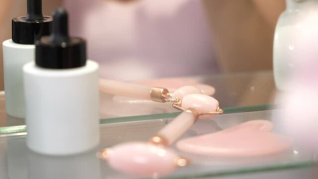 Girl uses Gua Sha and Roller for facial care in front of a mirror