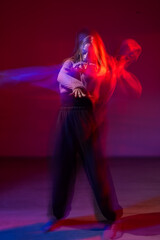 A young woman dances contemporary dances in blue and red light. Long exposure. Vertical photo. 