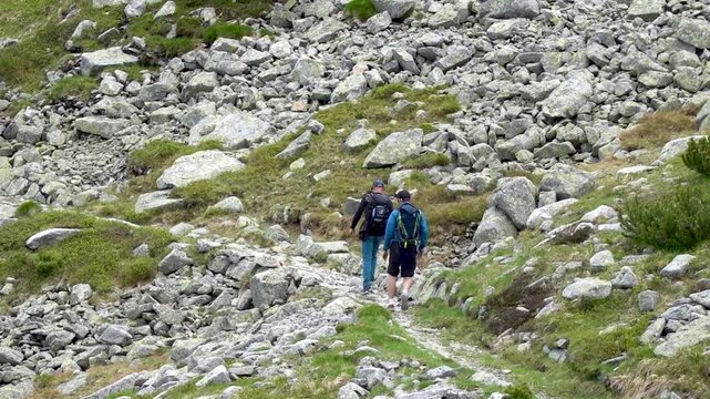 Two tourists walk at a sporty pace along the rocky trail to the top of Lomnicke sadle in the High Tatras in Slovakia