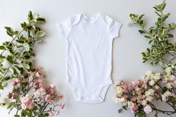White blank baby bodysuit vest mockup surrounded by flowers 