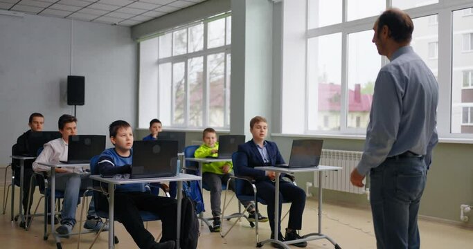 Middle-Aged Teacher And Group Of Schoolboys In Computer-Based Class, Education And Learning