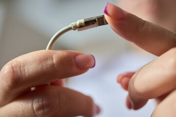 The image shows a closeup of someone gripping a lightning cable that appears to be damaged