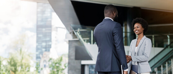 You're hired. African American business people shaking hands near office building after job interview. Copy space