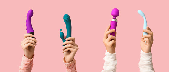 Hands of young women holding sex toys on pink background