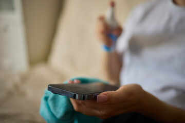 A person is using a microfiber cloth to clean their smartphone for hygiene purposes